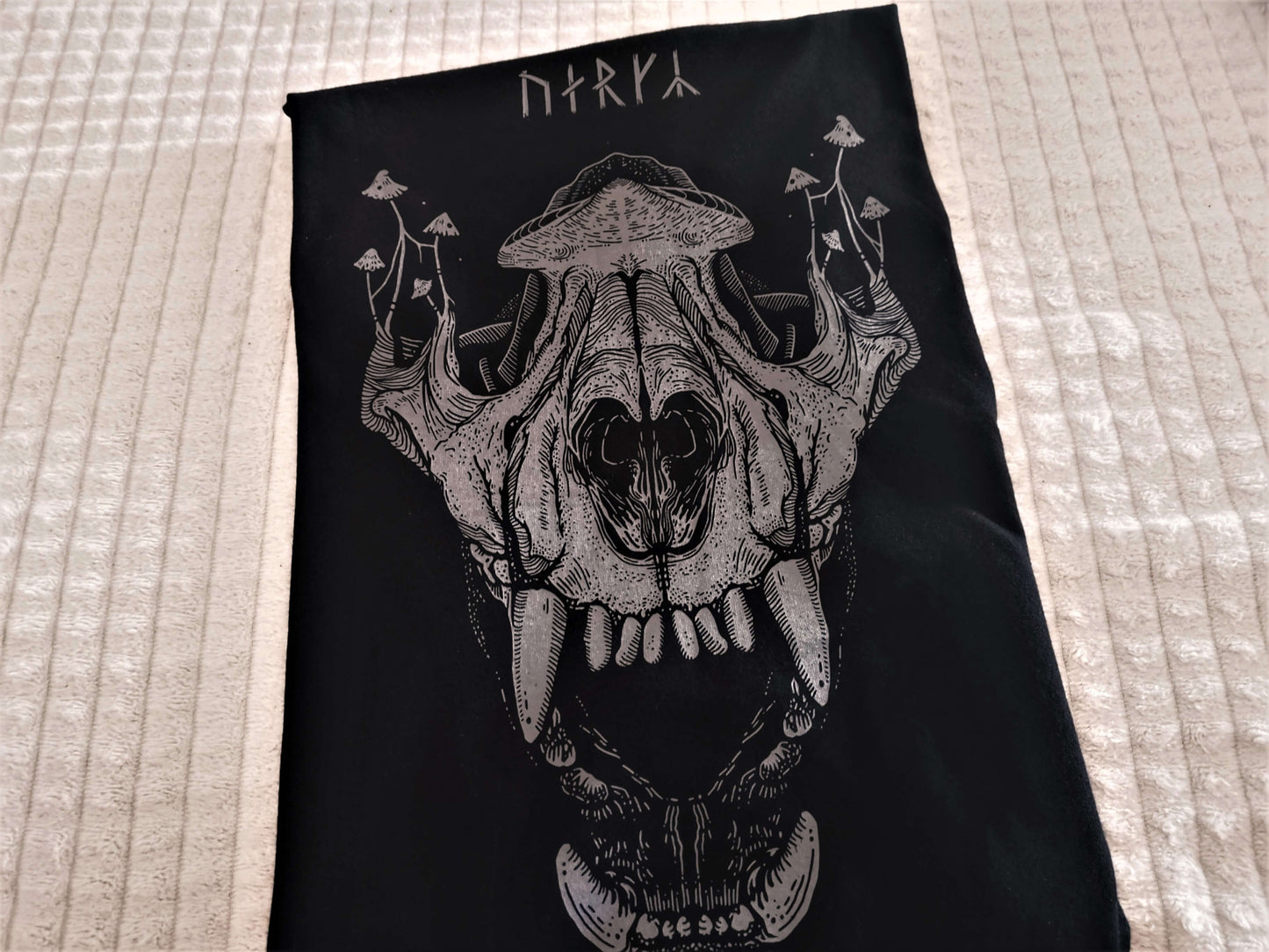 Grey print of a gothic wolf skull and mushrooms on top of it on a black goblincore t-shirt.
