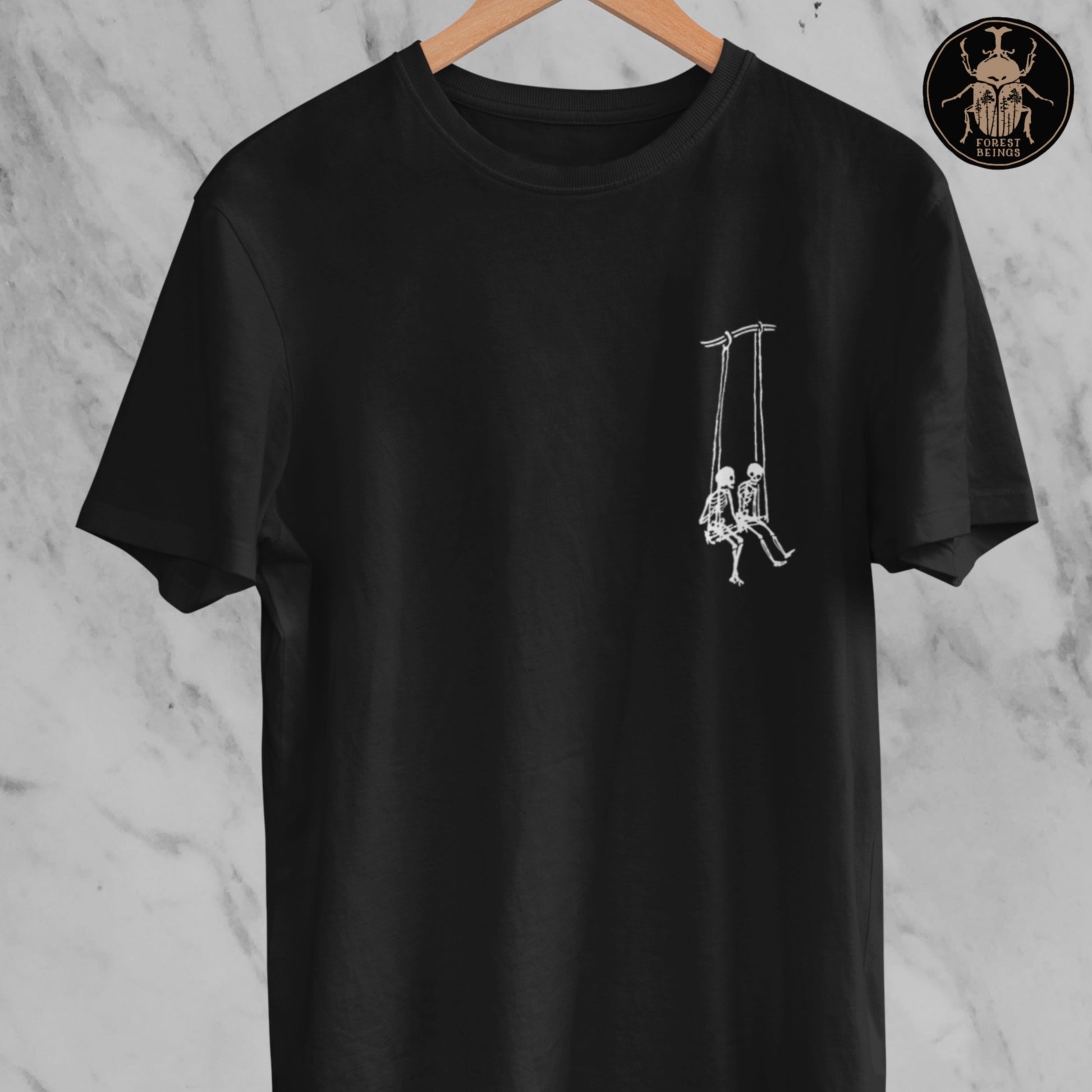 A gothic simple minimalistic t-shirt with two cute skeletons swinging on a swing. 