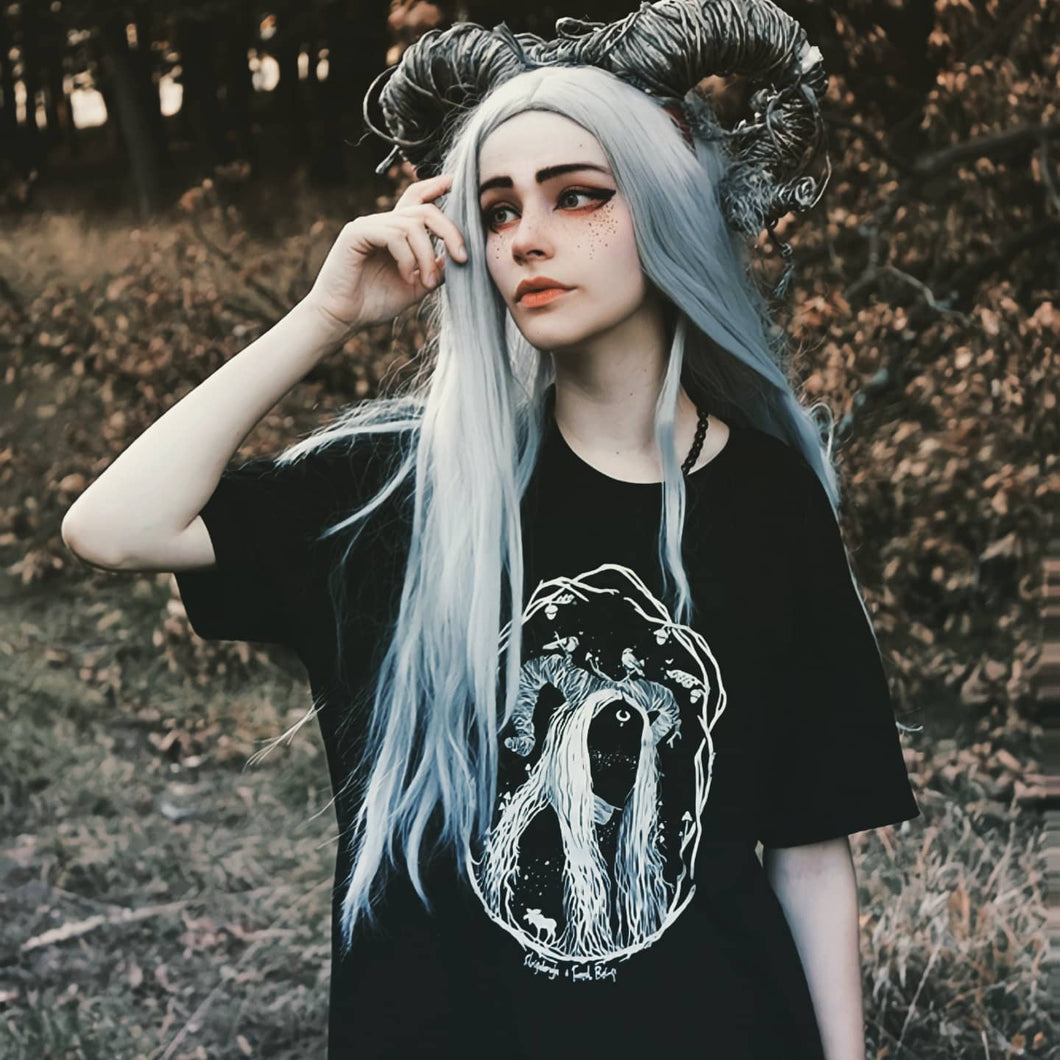 A forest witch with horns in the forest wearing a witchy gothic oversized t-shirt.