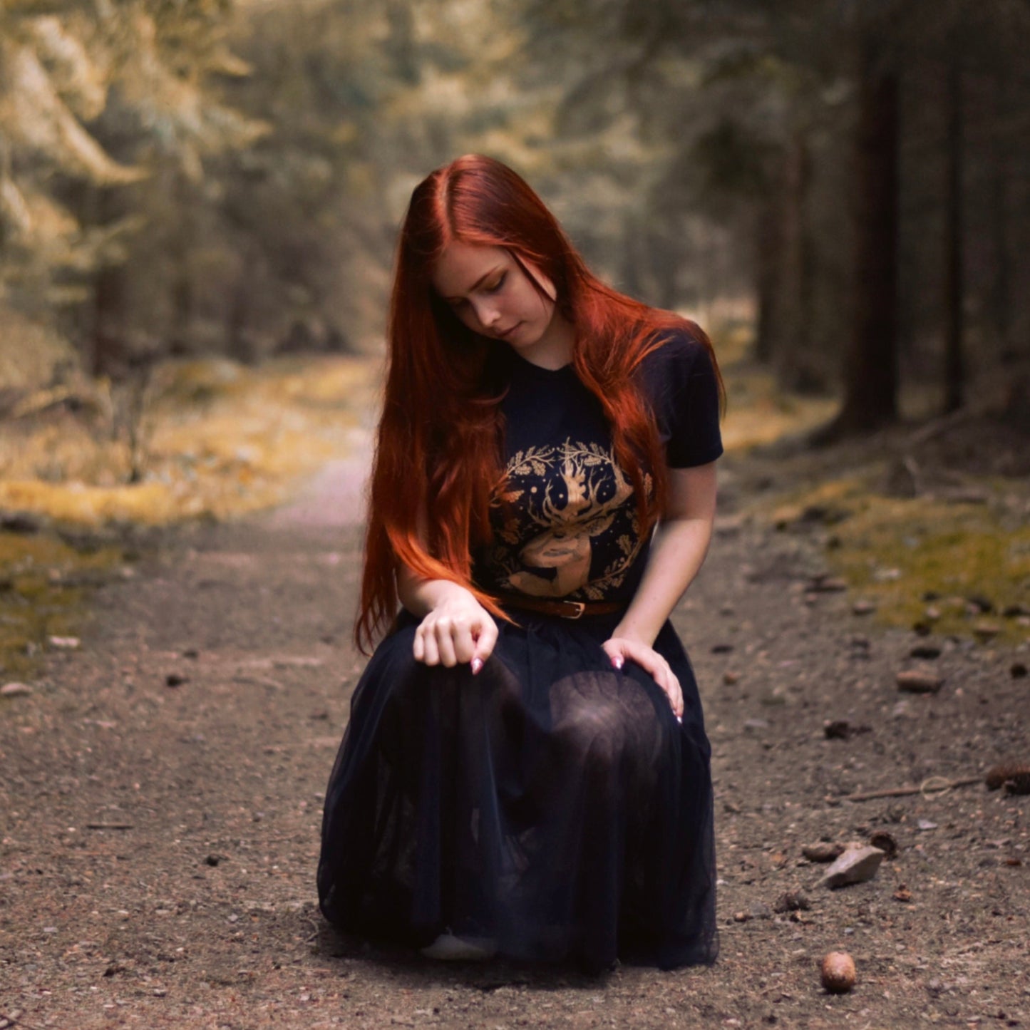A redhead girl kneel in the middle of the forest