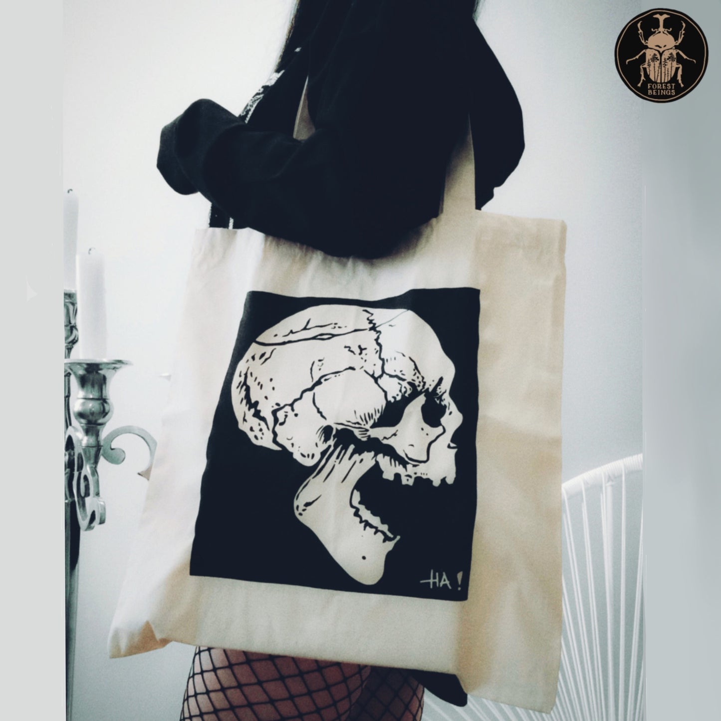 A black laughing skull on a gothic aesthetic edgy tote bag worn by a goth girl in black.