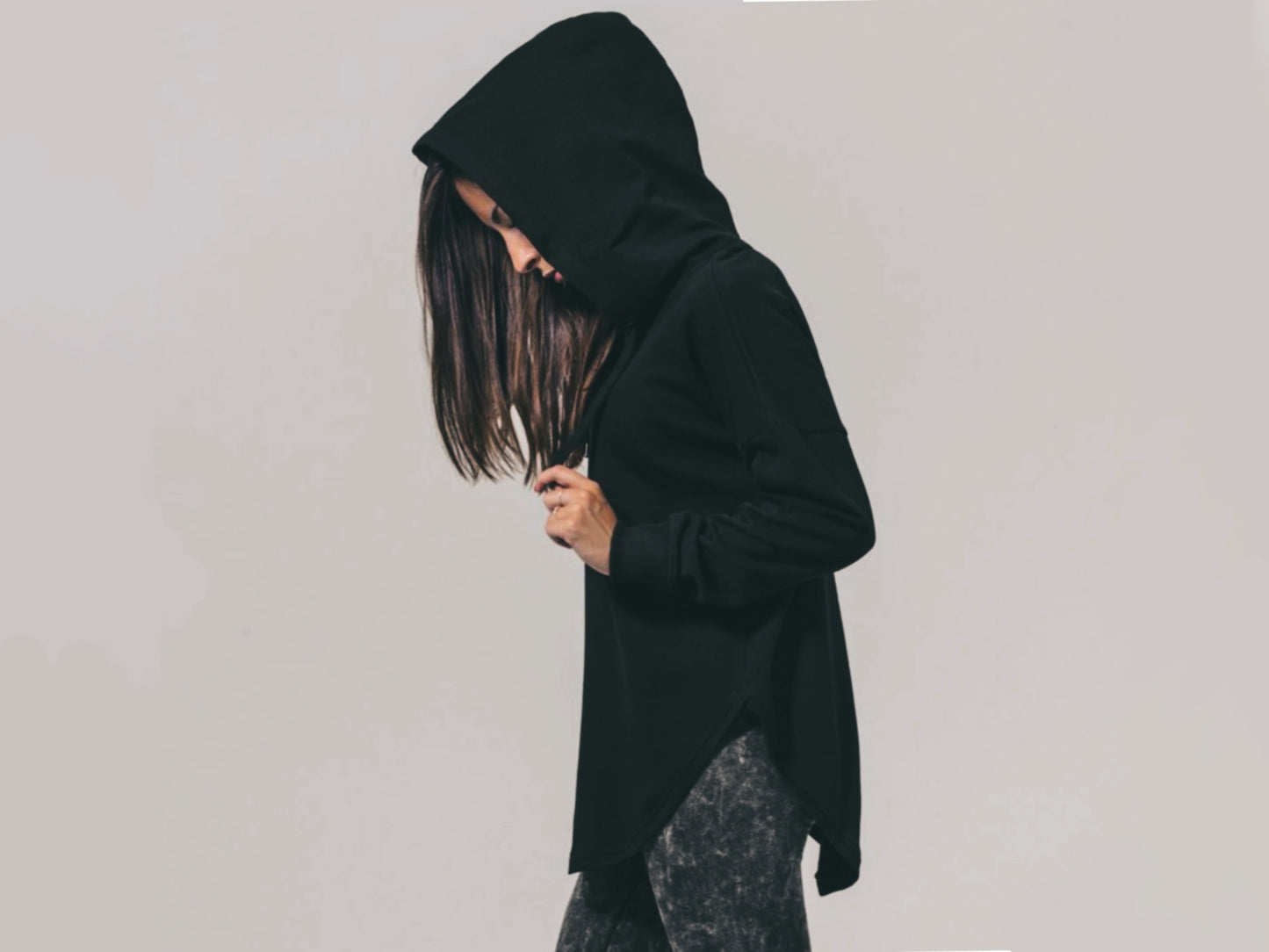A woman is wearing a witchcore gothic oversized loose fit black hoodie.The outfit will be best described as aesthetic soft goth or witchy.